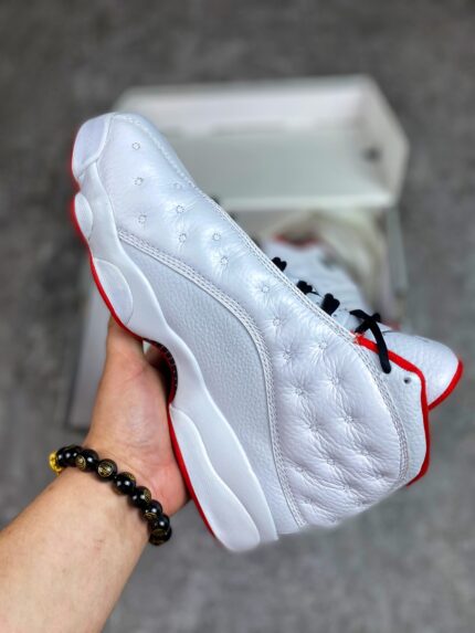 White sports shoes with red details, black laces