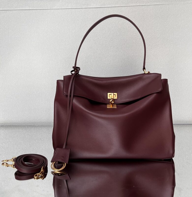 A dark red leather handbag with a detachable shoulder strap and a metal clasp.